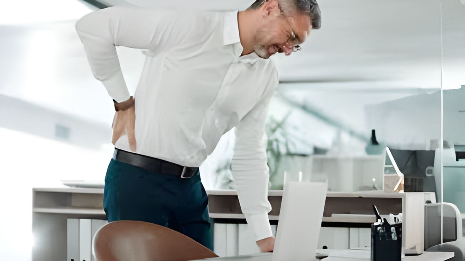 கணினி முன் அமர்ந்து வேலை செய்யும் போது முதுகு வலியால் அவதிப்படும் ஒரு இளைஞர்